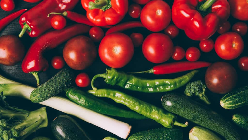 Red and green chili peppers mixed in with cherry tomatoes, cucumbers, zucchini, broccoli and leeks