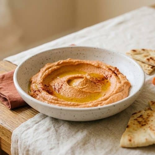 Red pepper hummus: roasted red bell pepper and smoked paprika blended into creamy hummus, sweet and smoky with barely any heat.